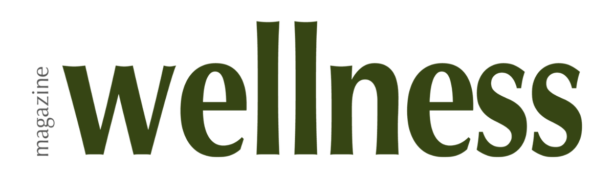 Evatasha Beauty The logo for wellness magazine, featuring the word 'wellness' in a dark olive green serif font with 'magazine' printed vertically in a smaller gray font to the left, set against a solid white background.